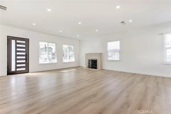an empty room with wooden floor fireplace and windows