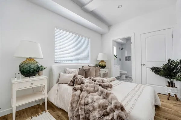 a bedroom with a bed a potted plant and a window