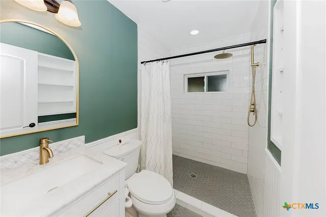 a bathroom with a granite countertop toilet and a sink
