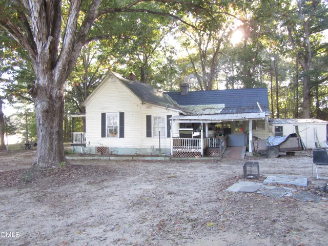 a view of a house with a yard and large tree