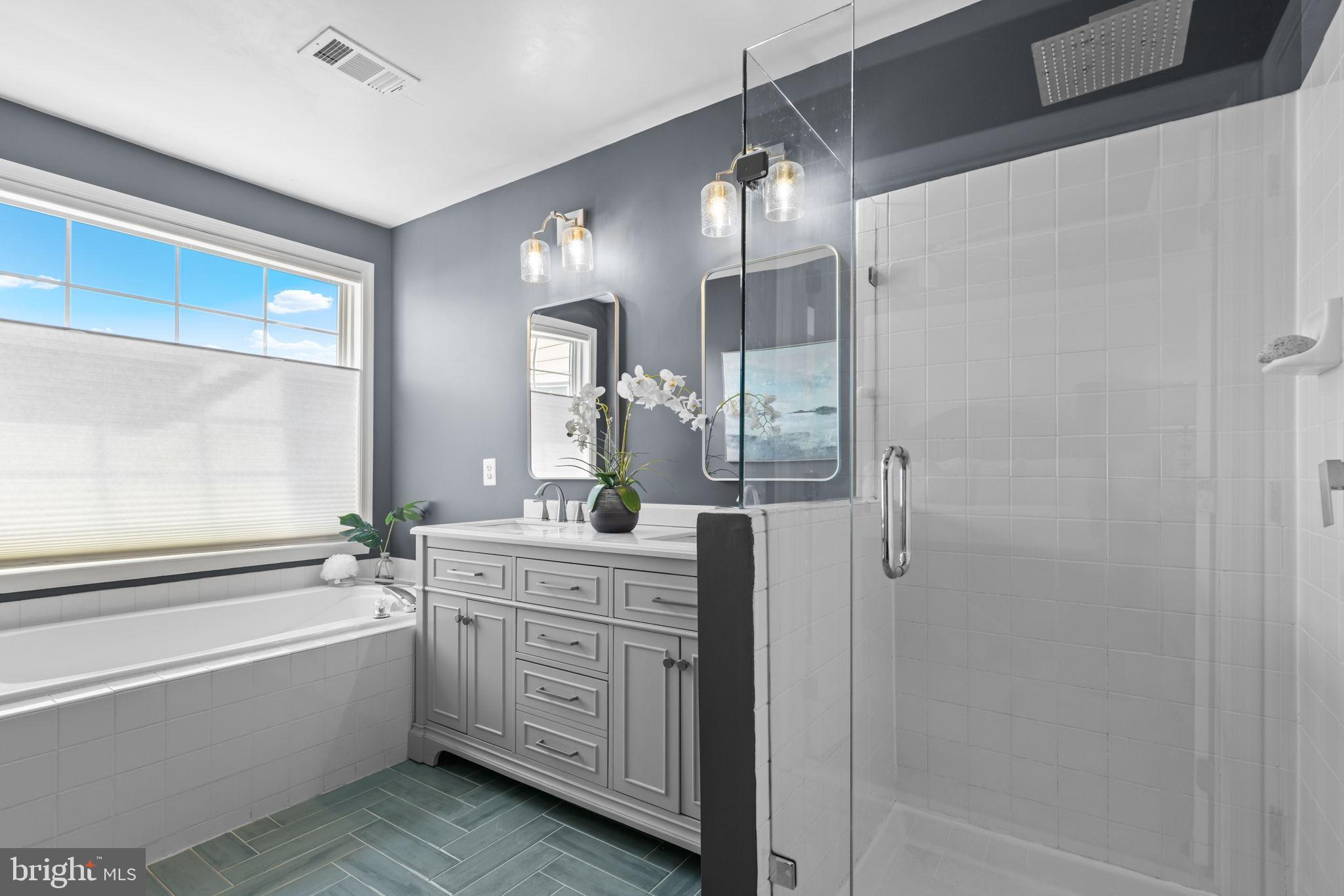 6311 Burgundy Leaf Lane Alexandria, VA 22312 - Photo 21 of 33 a bathroom with a double vanity sink a large mirror a bathtub and shower