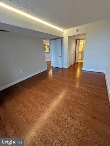 a view of an empty room with window and wooden floor