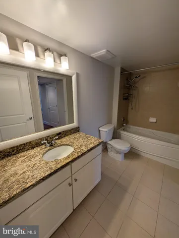 a bathroom with a granite countertop sink a toilet and a shower