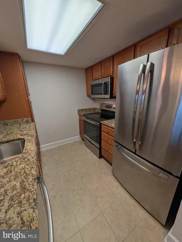 a kitchen with granite countertop a refrigerator and a stove top oven