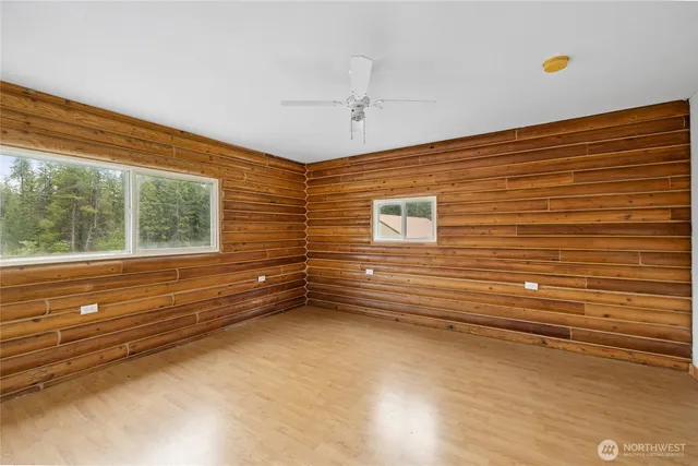 a view of empty room with wooden floor and fan