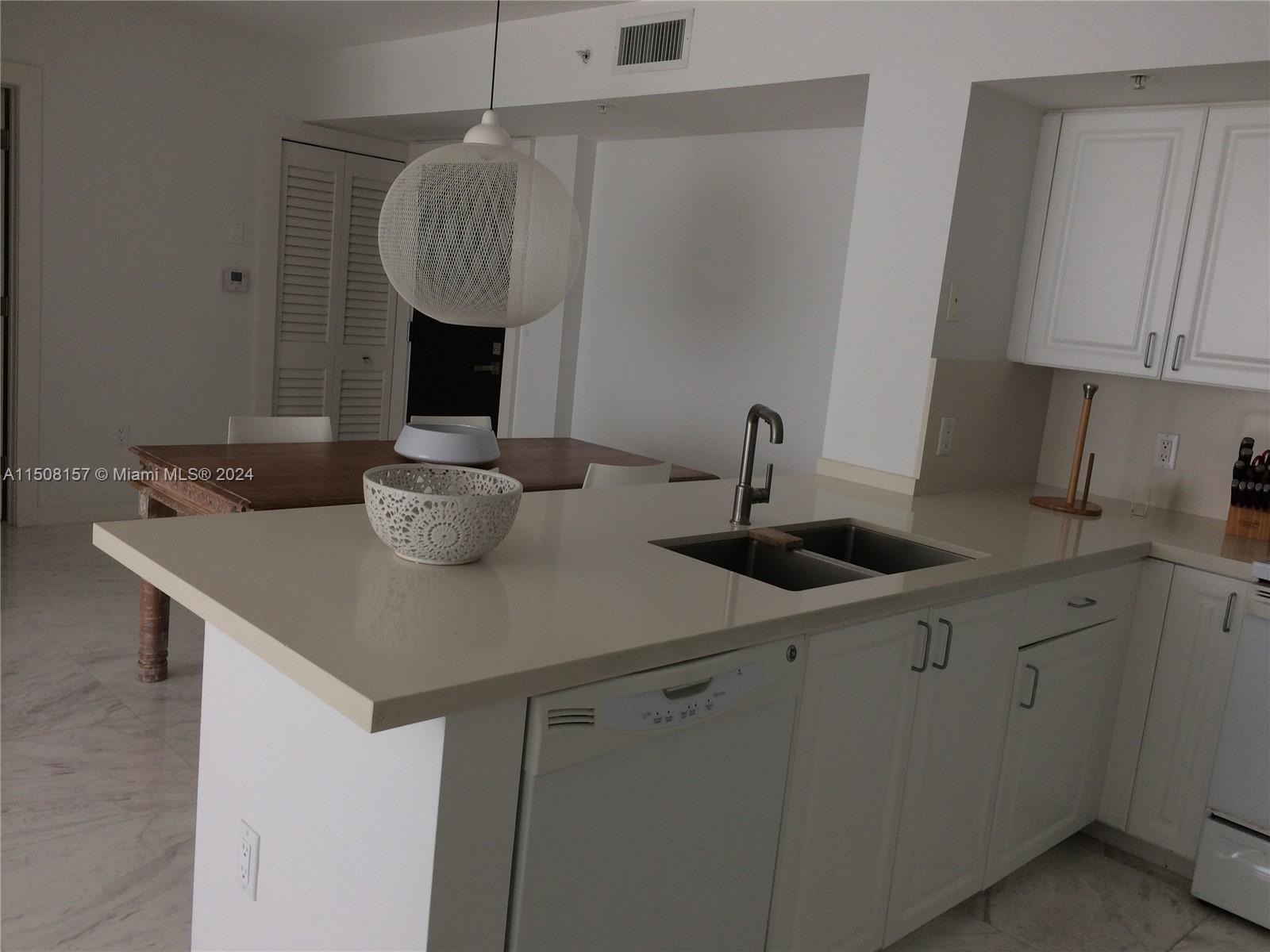 90 Alton Road, Unit 2503 Miami Beach, FL 33139 - Photo 12 of 23 a kitchen with a sink cabinets and a table