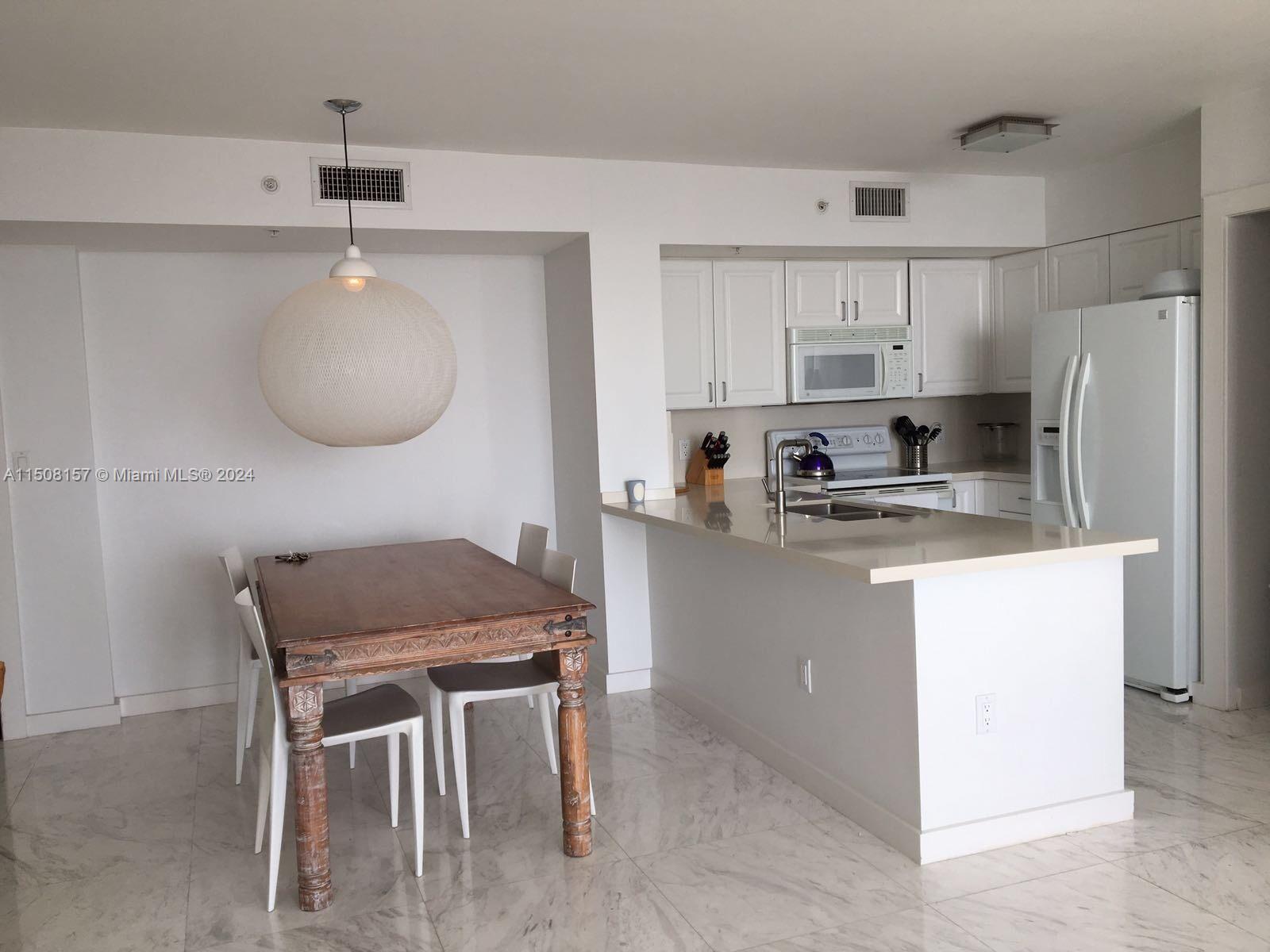 90 Alton Road, Unit 2503 Miami Beach, FL 33139 - Photo 3 of 23 a kitchen with kitchen island a stove a table and chairs