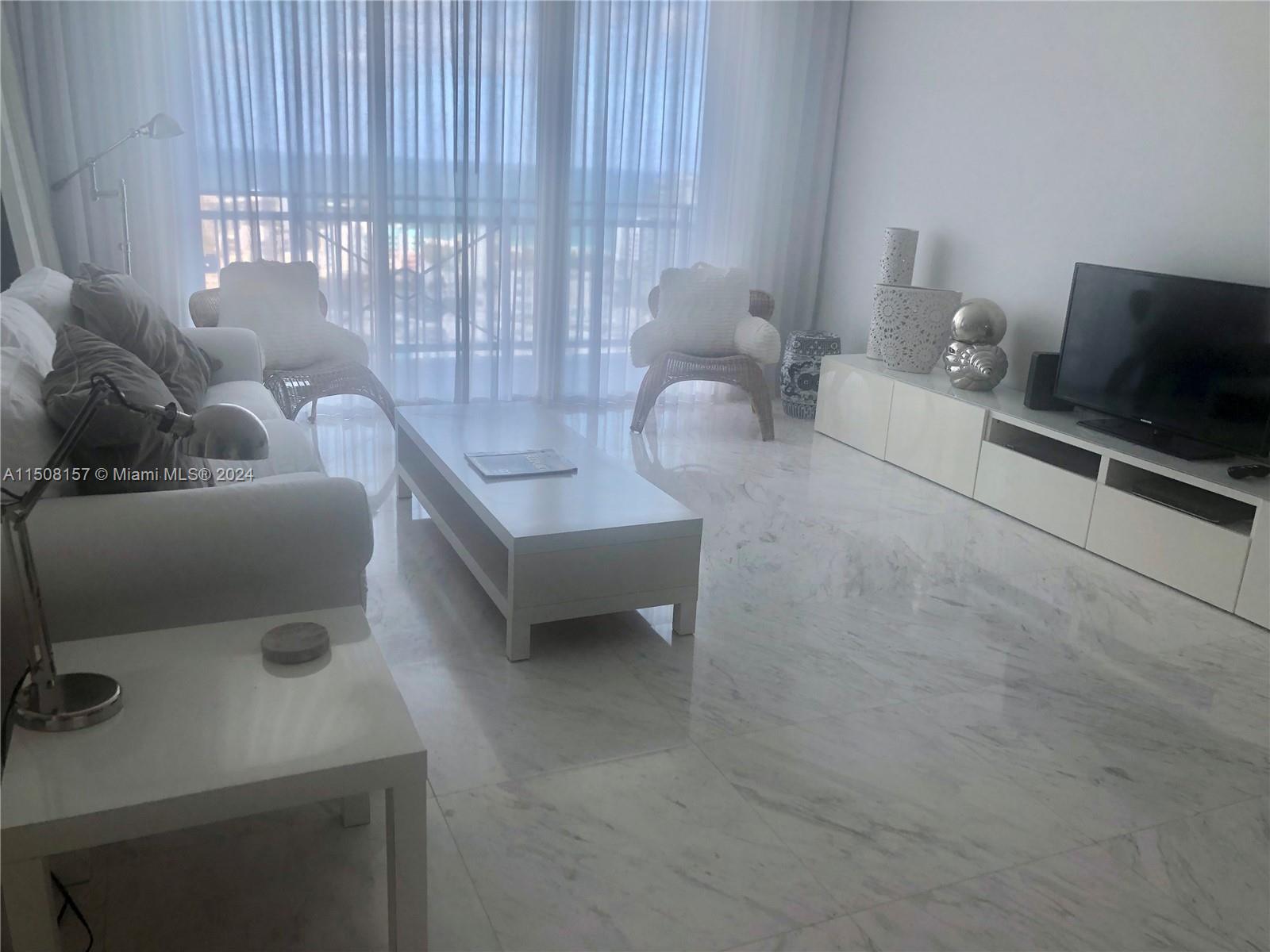 90 Alton Road, Unit 2503 Miami Beach, FL 33139 - Photo 4 of 23 a living room with furniture and a flat screen tv