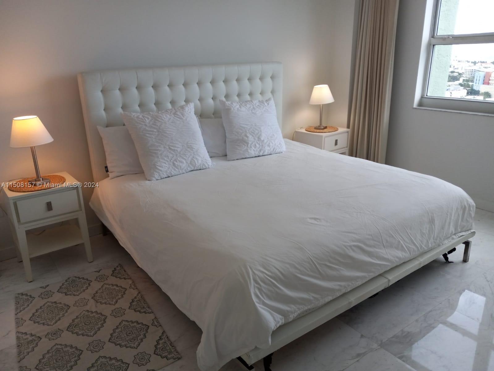 90 Alton Road, Unit 2503 Miami Beach, FL 33139 - Photo 6 of 23 a large bed sitting in a bedroom next to a lamp