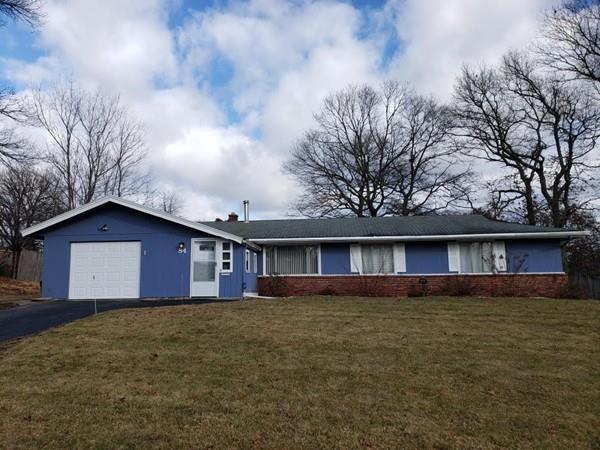 a front view of house with yard and trees in the background