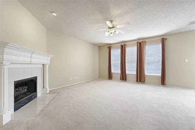 a view of an empty room with chandelier fan and fire place