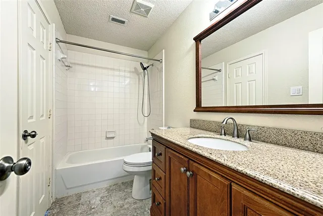 a bathroom with a granite countertop sink a toilet and shower