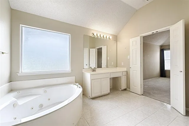 a large spacious bathroom with a tub a sink and mirror