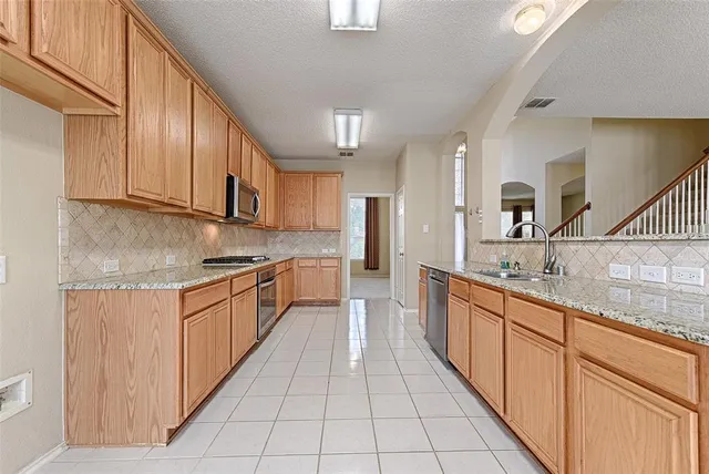 a large kitchen with stainless steel appliances granite countertop a sink and cabinets