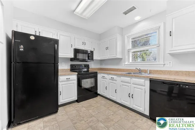 a kitchen with white cabinets and refrigerator