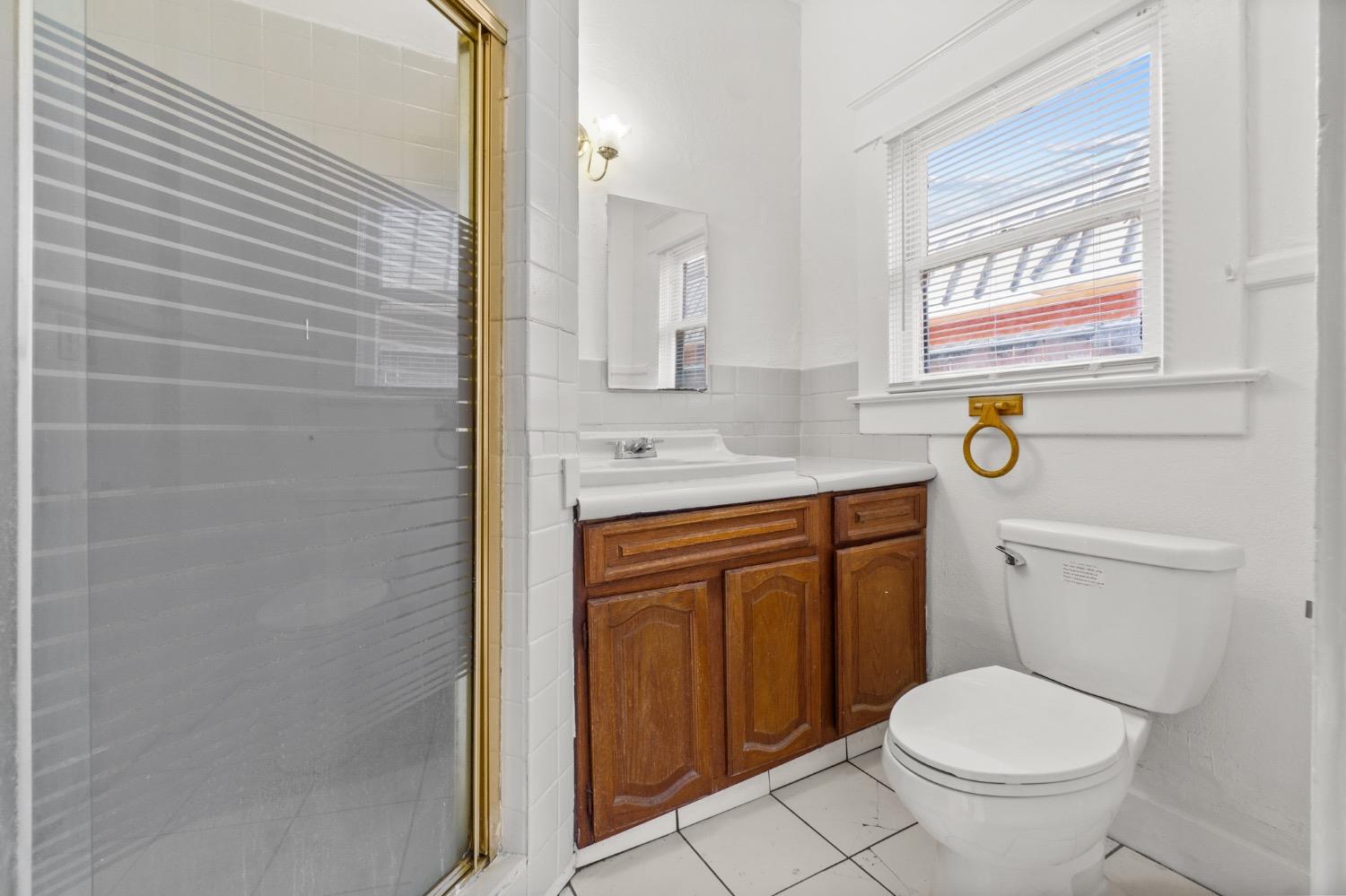 4354 East Kings Canyon Road Fresno, CA 93702 - Photo 52 of 87 a bathroom with a granite countertop toilet a sink a mirror and a shower