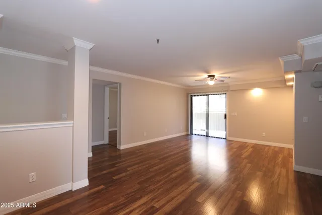 a view of an empty room with wooden floor and a window