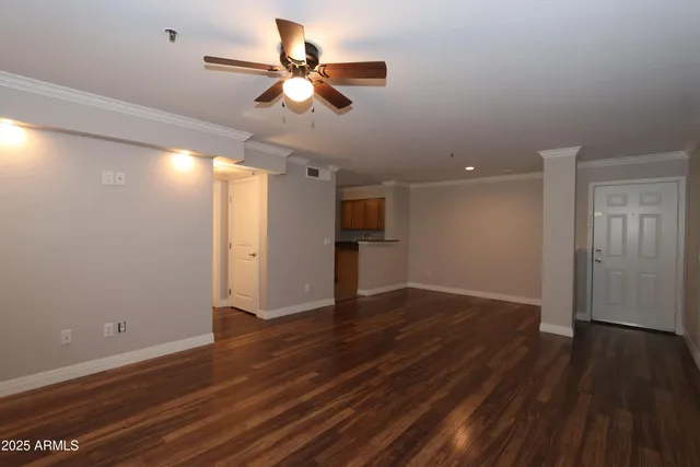 a view of an empty room with wooden floor and a ceiling fan