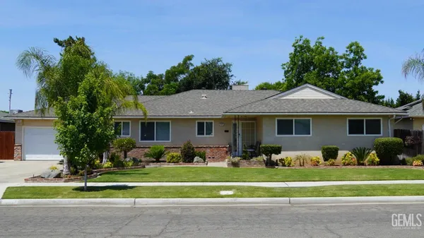 a front view of a house with a garden and trees
