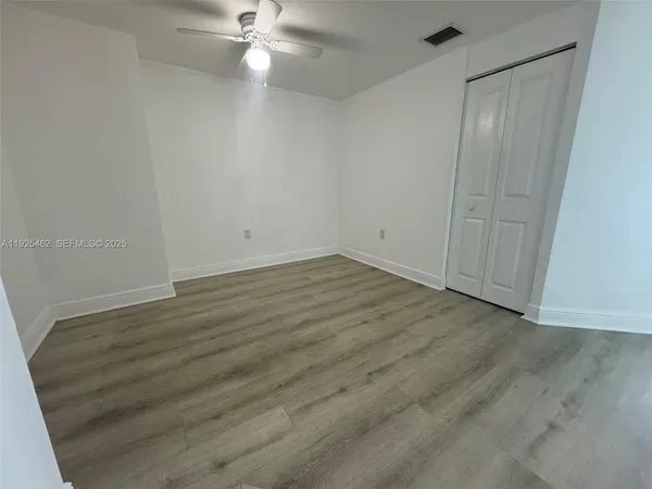 an empty room with wooden floor and fan