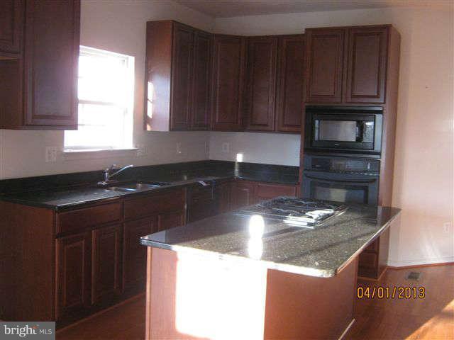 3406 Kidder Road Clinton, MD 20735 - Photo 13 of 26 a kitchen with granite countertop wooden cabinets and a stove top oven
