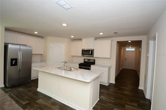 a kitchen with stainless steel appliances kitchen island granite countertop a refrigerator and a sink