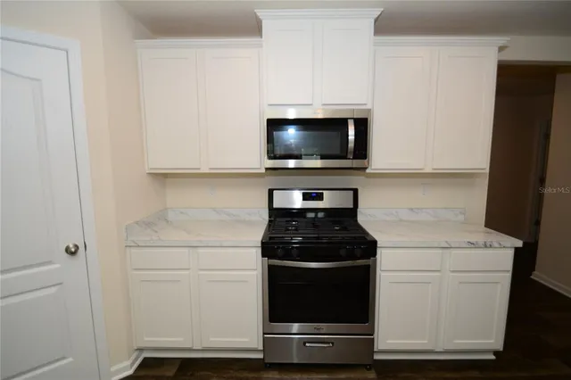 a kitchen with white cabinets and black appliances