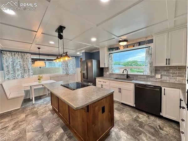 a kitchen with a stove a sink a counter top space and living room view