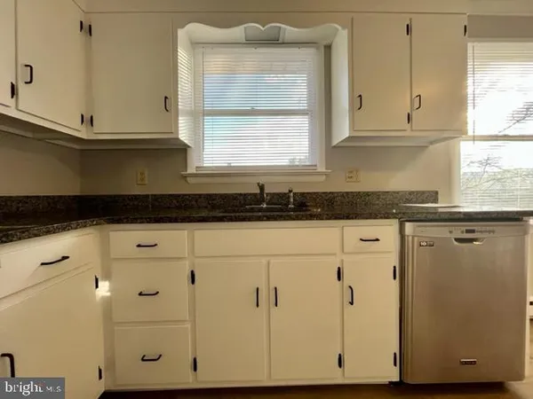 a kitchen with granite countertop white cabinets and sink