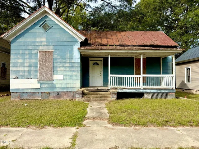 a view of a house with a yard plants and large tree