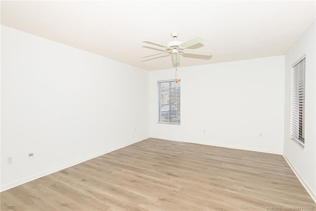 5373 Southeast Miles Grant Road, Unit C102 Stuart, FL 34997 - Photo 12 of 21 an empty room with wooden floor fan and windows