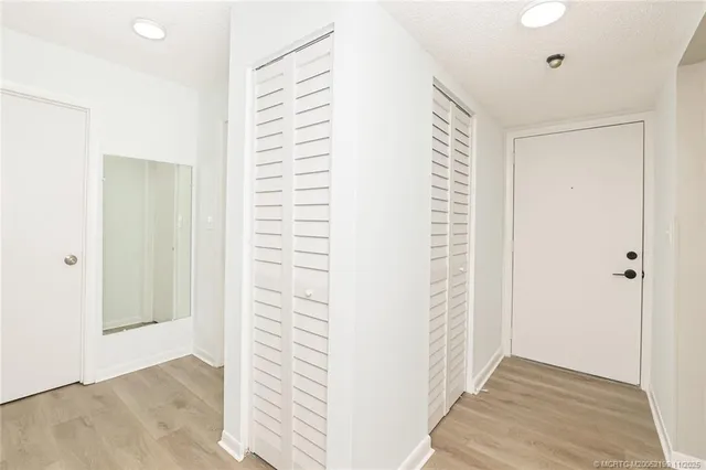 a view of a hallway with wooden floor and closet