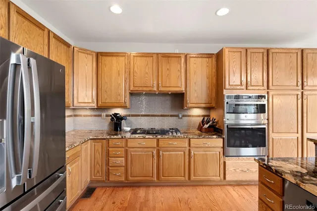 a kitchen with stainless steel appliances granite countertop a stove a refrigerator a sink dishwasher with wooden cabinets and a refrigerator