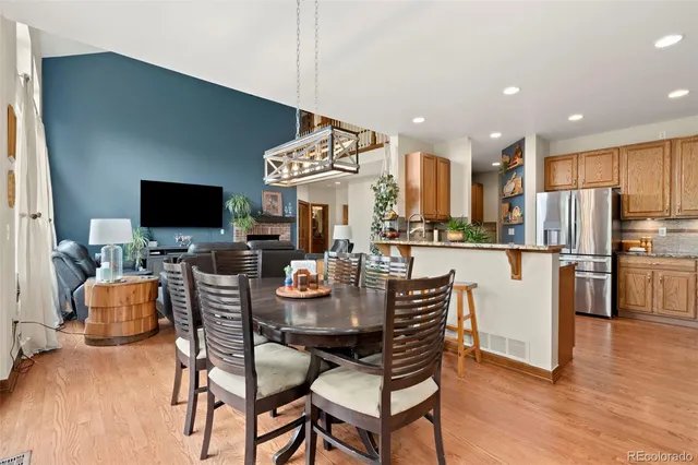a dining room with stainless steel appliances kitchen island granite countertop a table chairs and a refrigerator