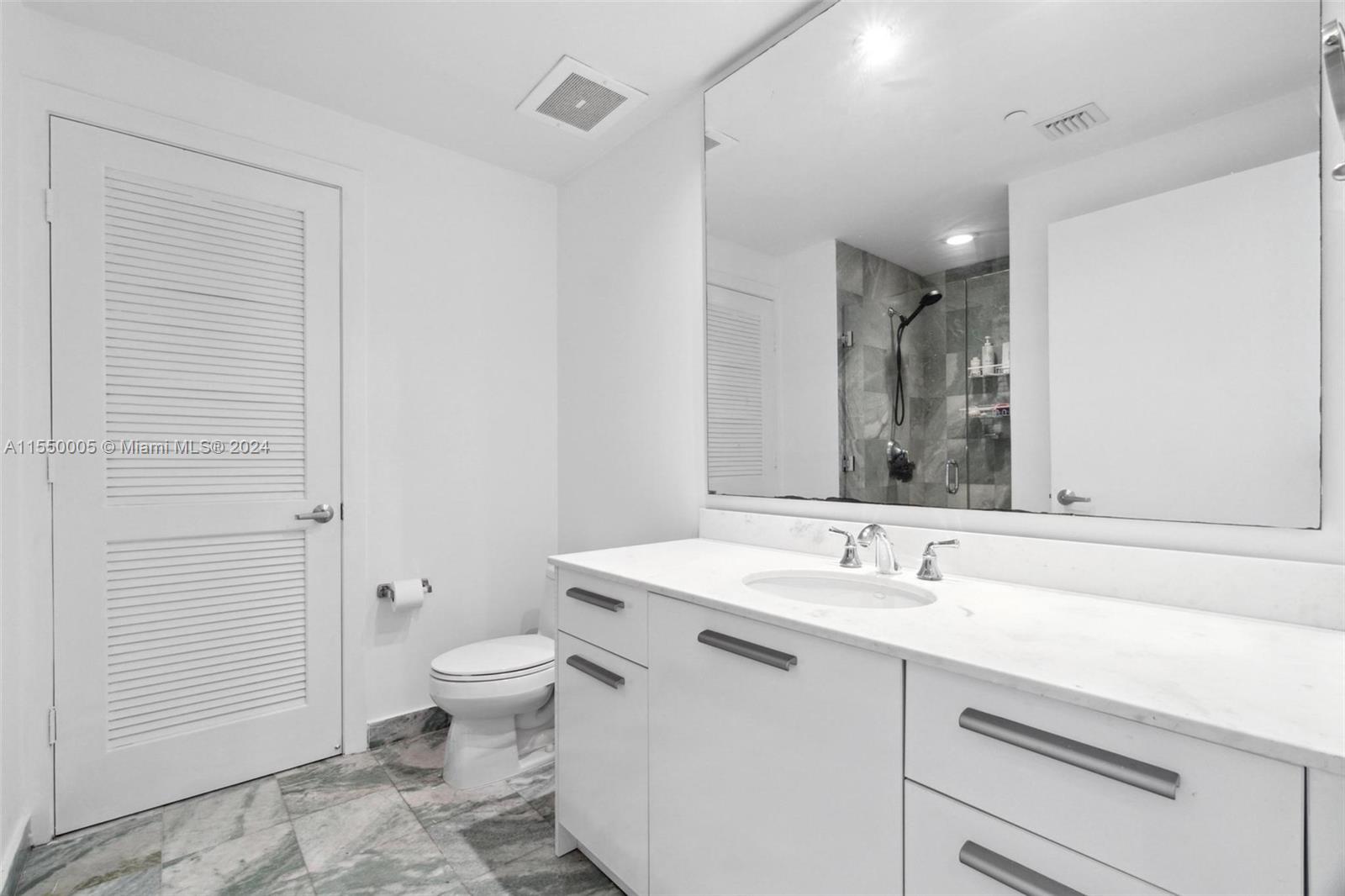 1050 Brickell Avenue, Unit 2422 Miami, FL 33131 - Photo 13 of 21 a bathroom with a sink a toilet a shower and a mirror