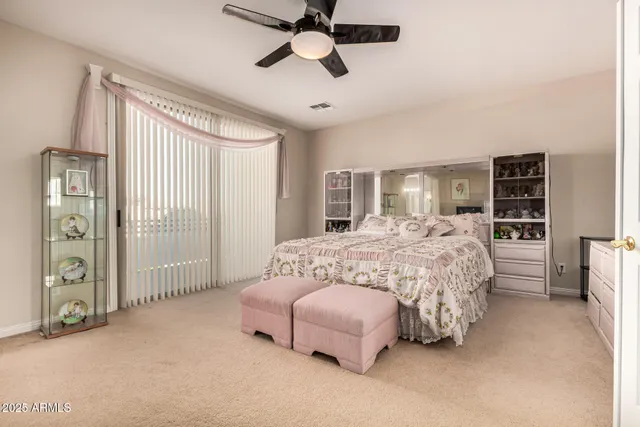 a bedroom with a large bed and a chandelier fan