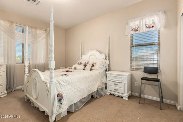 a bedroom with a bed table chair and a window