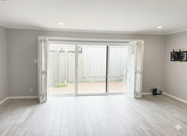 a view of an empty room with wooden floor and a window