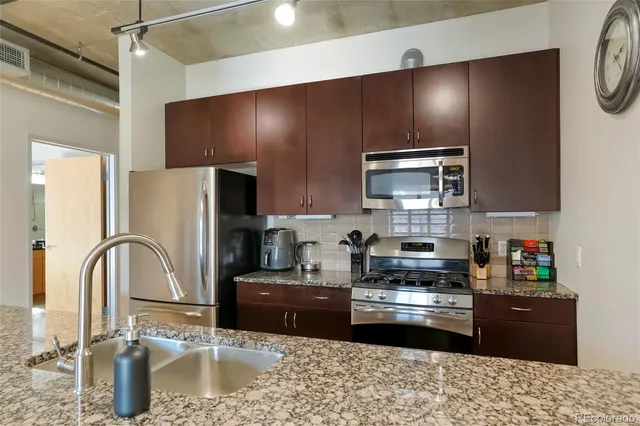 a kitchen with kitchen island granite countertop a sink stainless steel appliances and cabinets