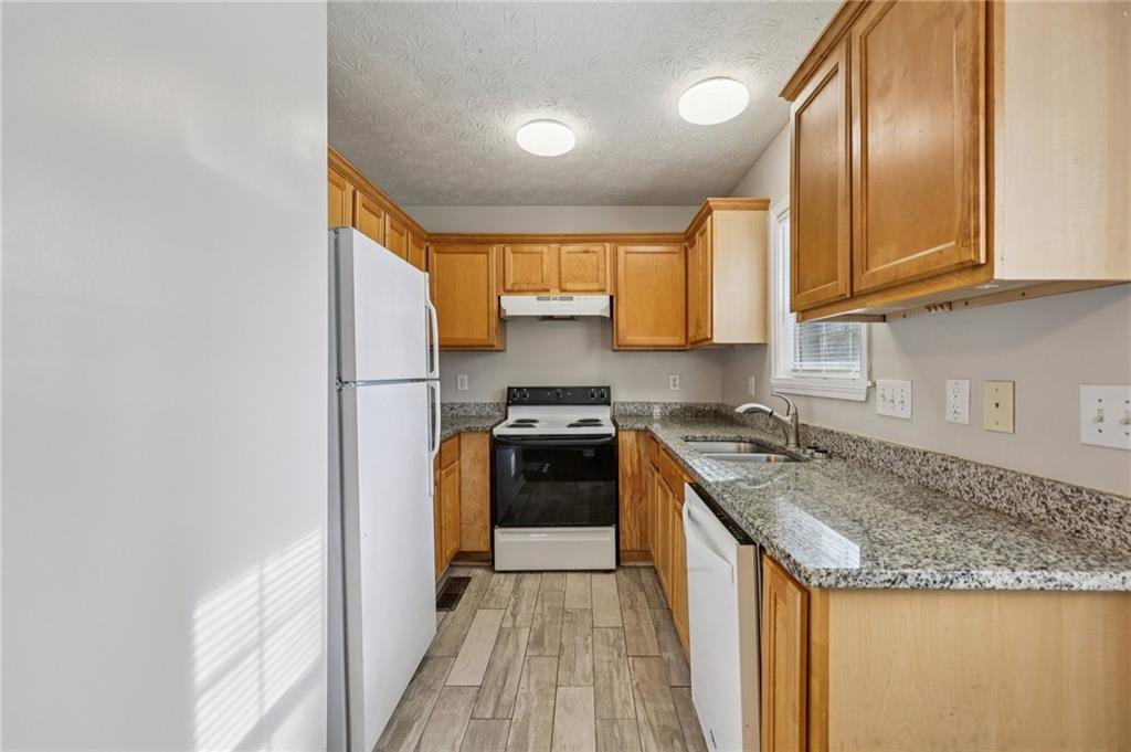 122 Nowell Street Monroe, GA 30655 - Photo 6 of 24 a kitchen with granite countertop wooden cabinets and a stove top oven