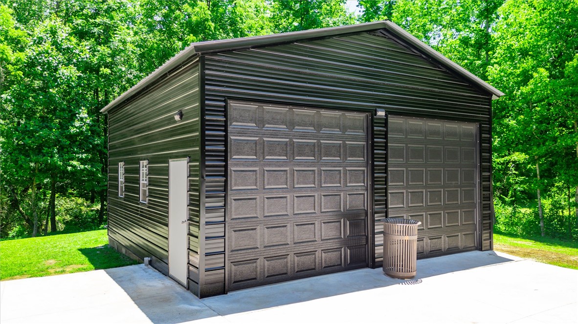 159 Cherokee Trail Easley, SC 29640 - Photo 30 of 38 A durable metal garage provides secure storage and workshop space amidst a verdant landscape.