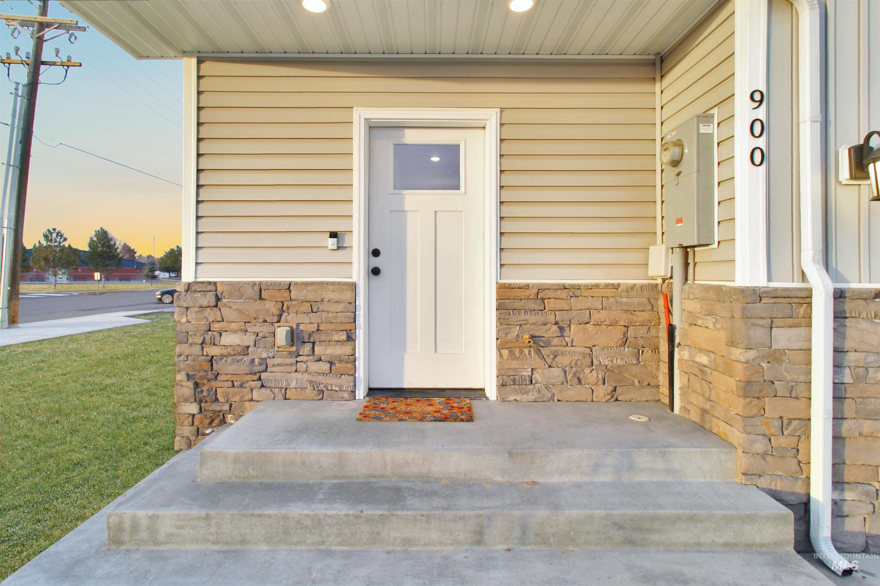 900 East 20th Street Burley, ID 83318 - Photo 4 of 31 Exterior entry at dusk with stone siding, a lawn, and a porch