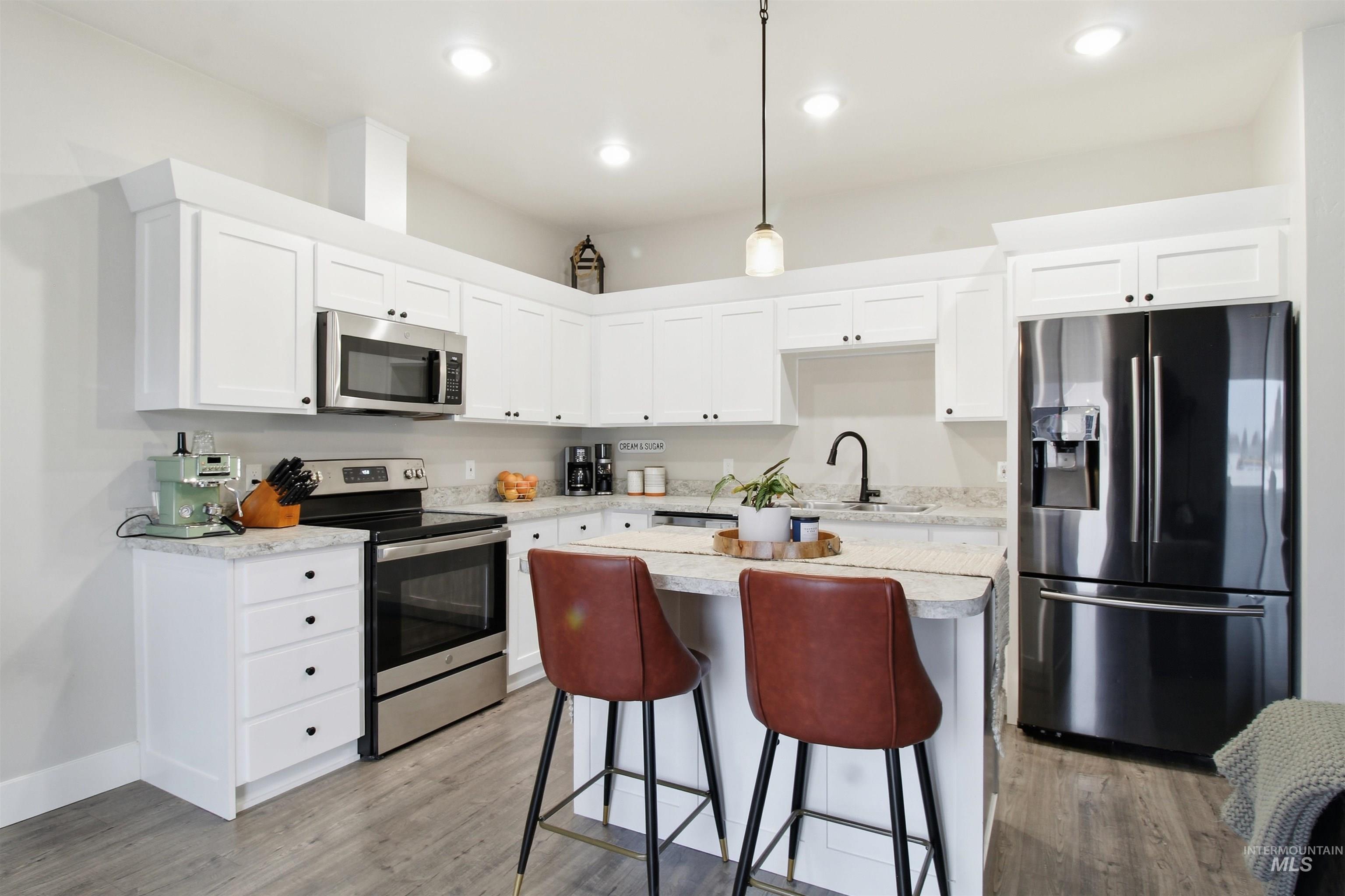 900 East 20th Street Burley, ID 83318 - Photo 6 of 31 Kitchen with appliances with stainless steel finishes, pendant lighting, white cabinets, a kitchen island, and a breakfast bar area