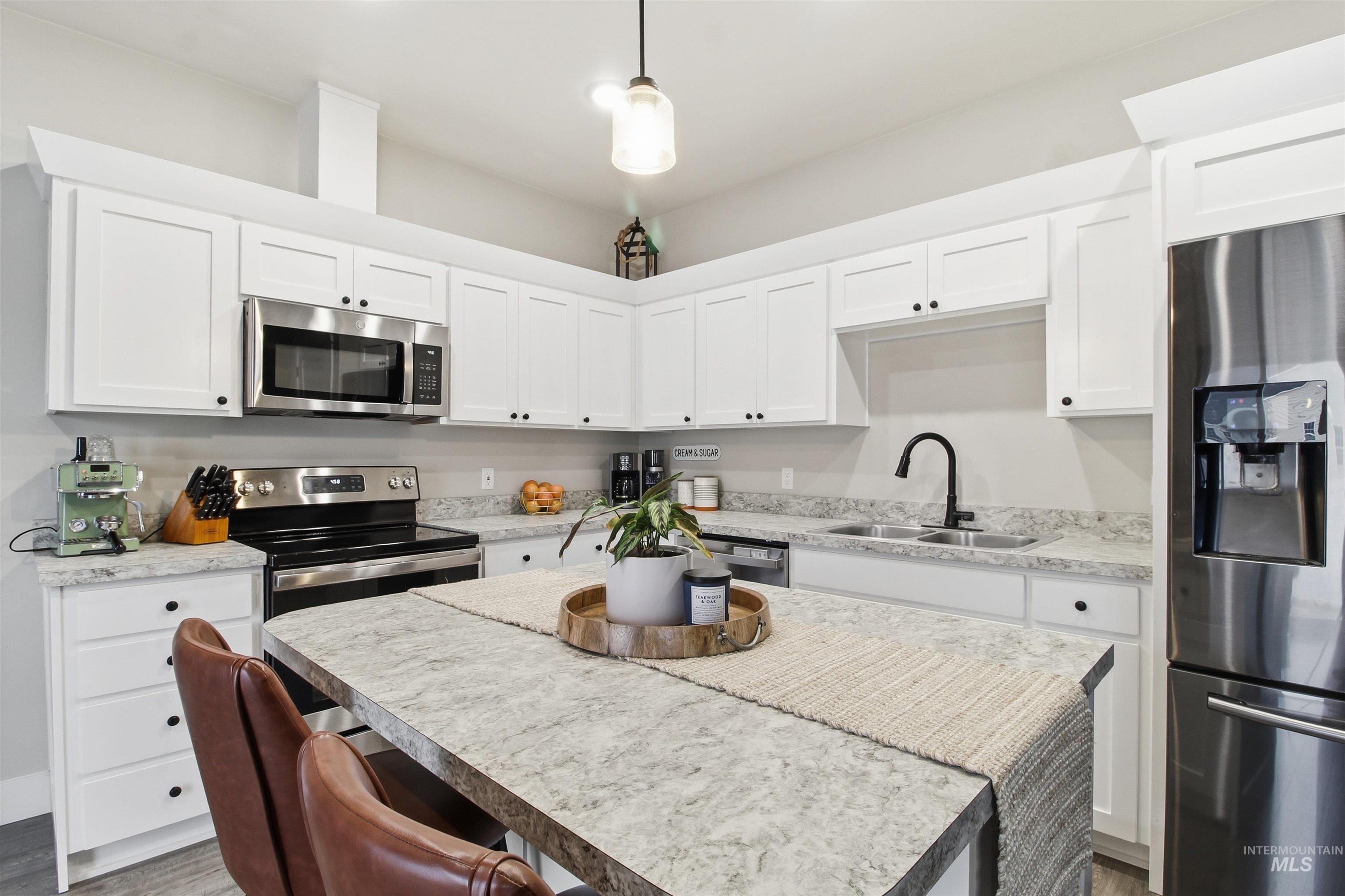 900 East 20th Street Burley, ID 83318 - Photo 7 of 31 Kitchen with stainless steel appliances, a center island, light countertops, hanging light fixtures, and white cabinets
