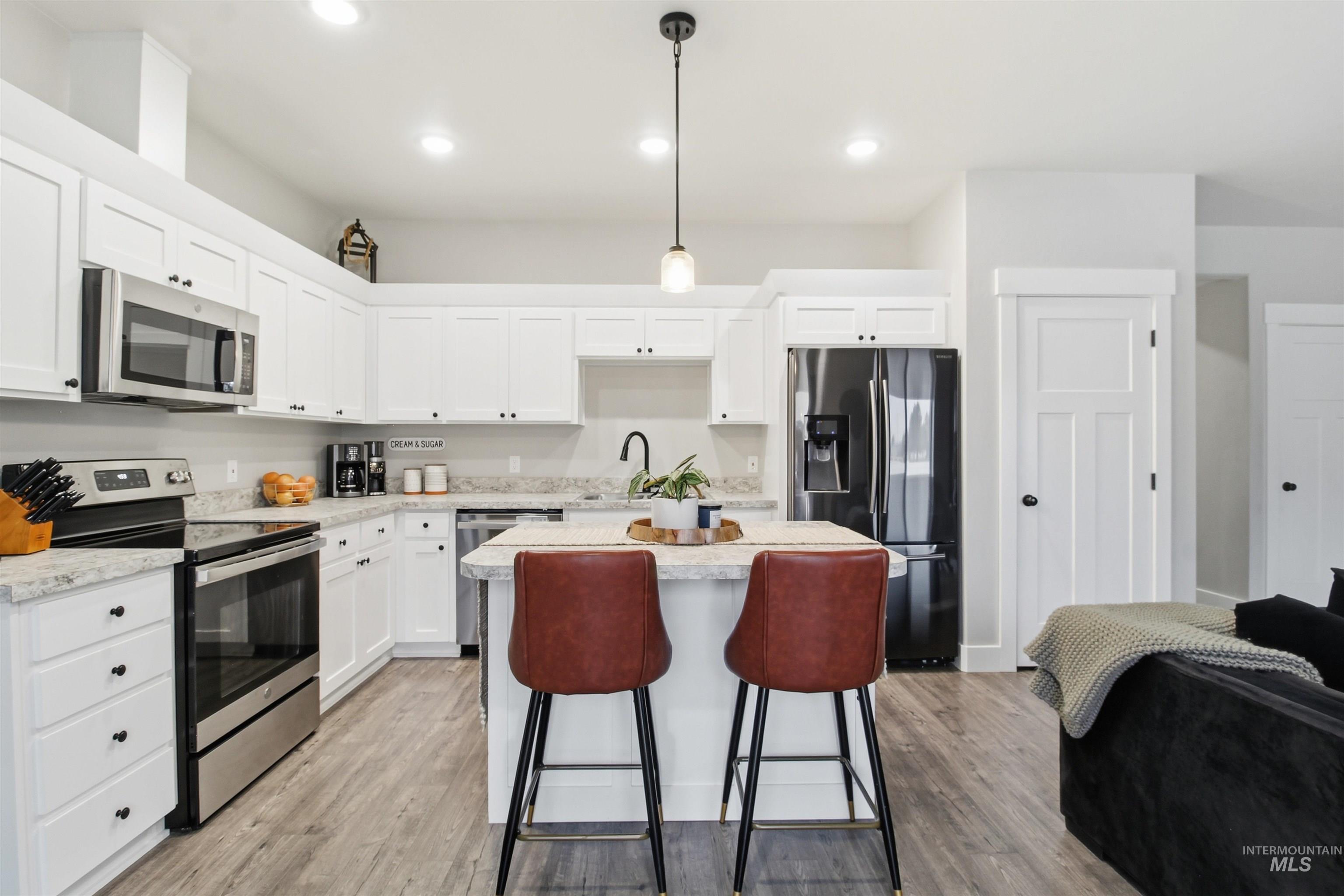 900 East 20th Street Burley, ID 83318 - Photo 8 of 31 Kitchen with stainless steel appliances, pendant lighting, white cabinets, a kitchen island, and a kitchen bar