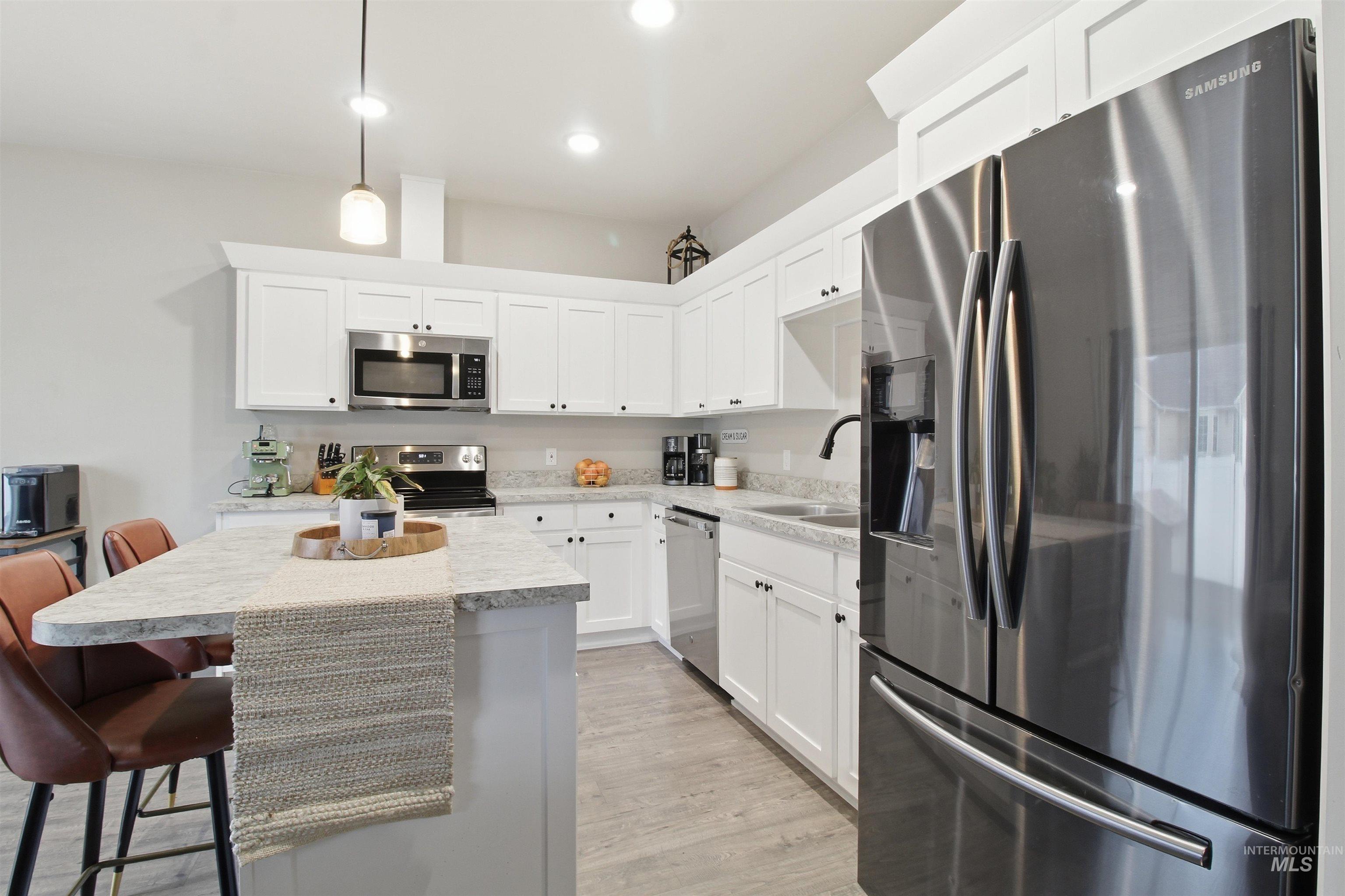 900 East 20th Street Burley, ID 83318 - Photo 10 of 31 Kitchen with appliances with stainless steel finishes, hanging light fixtures, a breakfast bar area, and white cabinets