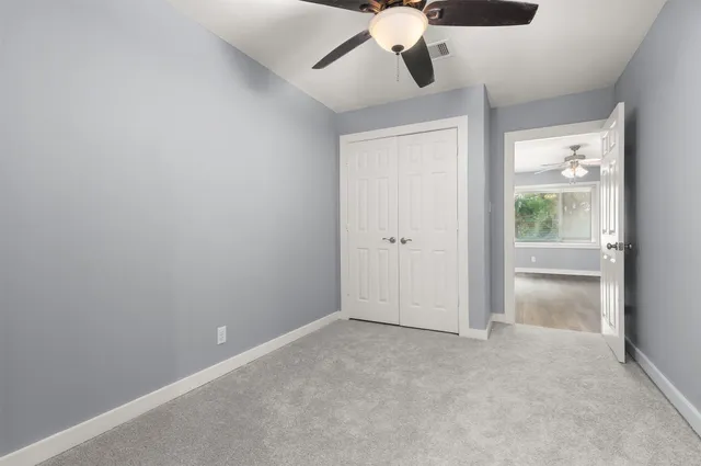 an empty room with a chandelier fan and closet