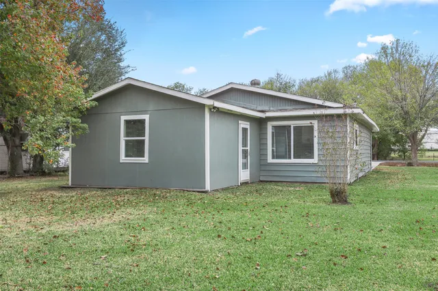 a backyard of a house with plants and large tree