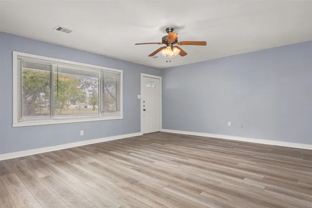 a view of an empty room with window and wooden floor