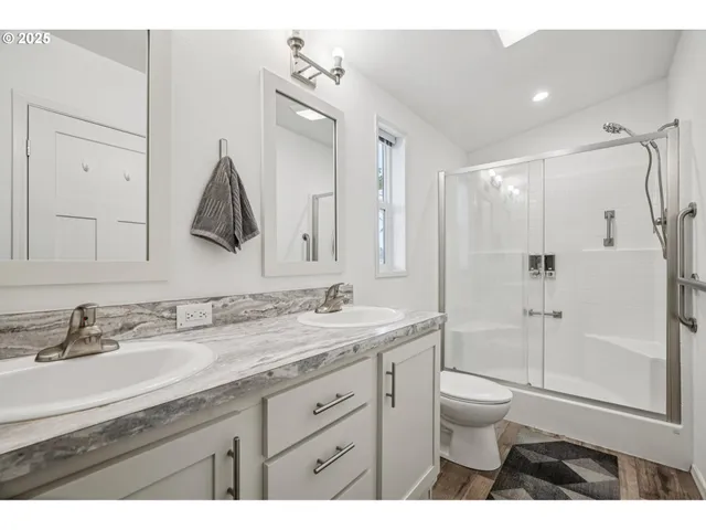 a bathroom with a granite countertop sink toilet a mirror a glass door and shower